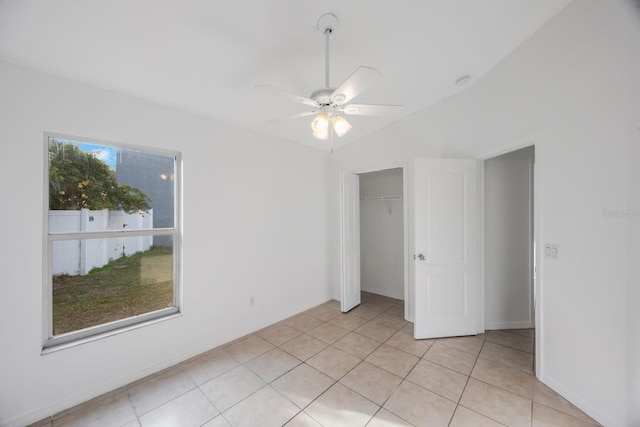 unfurnished bedroom featuring lofted ceiling, light tile patterned floors, ceiling fan, and a closet