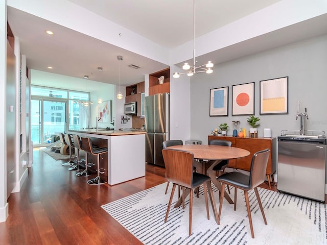 dining room with sink, hardwood / wood-style floors, and a notable chandelier