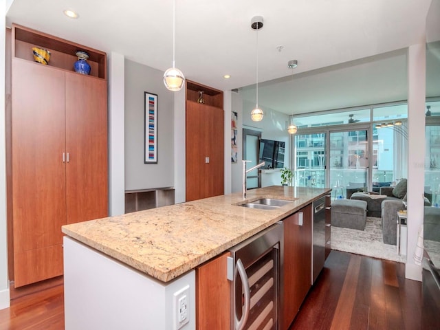 kitchen with light stone countertops, a kitchen island with sink, pendant lighting, and beverage cooler