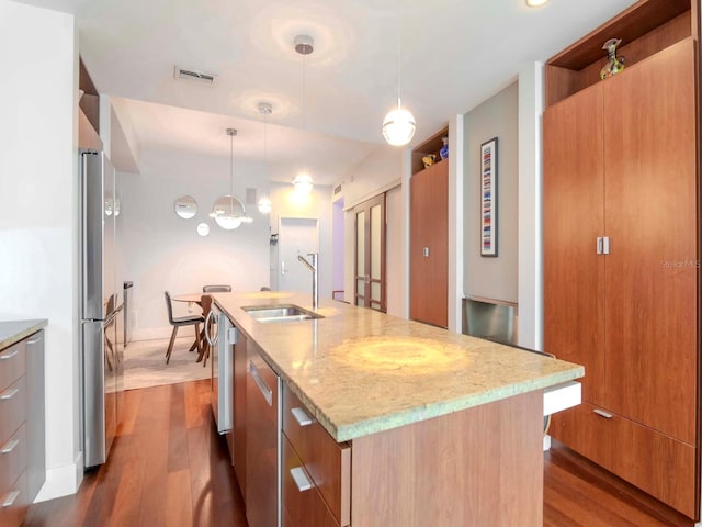 kitchen featuring sink, hanging light fixtures, dark hardwood / wood-style floors, and an island with sink