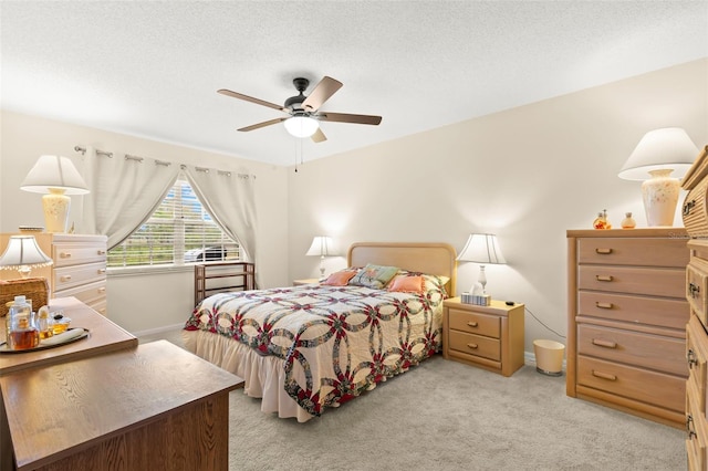 carpeted bedroom featuring ceiling fan and a textured ceiling