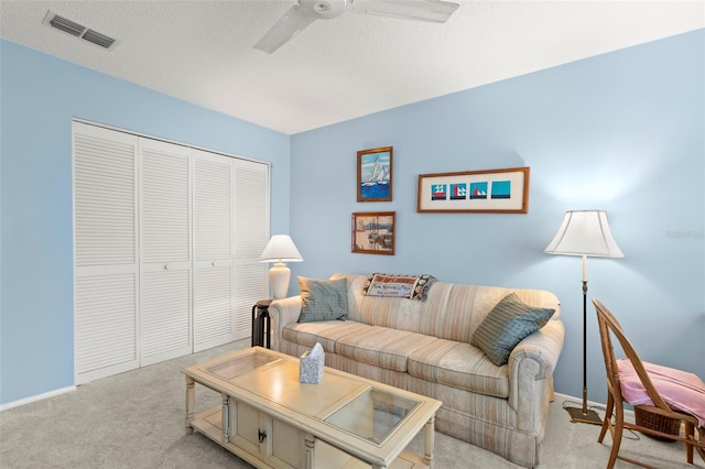 living room featuring light colored carpet, a textured ceiling, and ceiling fan