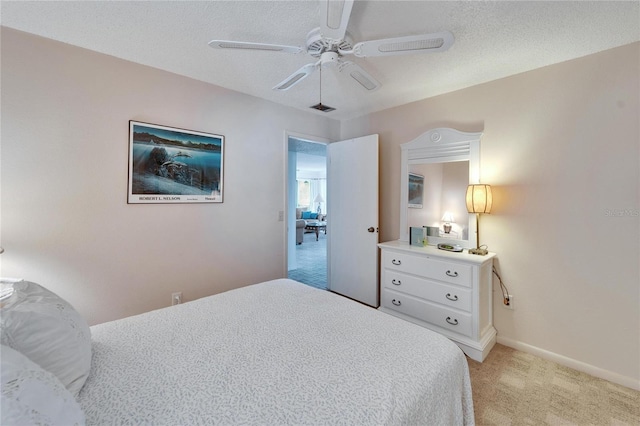 bedroom featuring light carpet, ceiling fan, and a textured ceiling