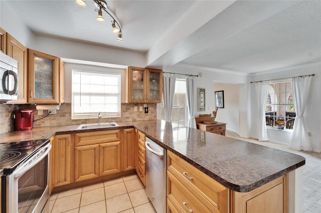 kitchen featuring sink, kitchen peninsula, a wealth of natural light, stainless steel appliances, and decorative backsplash