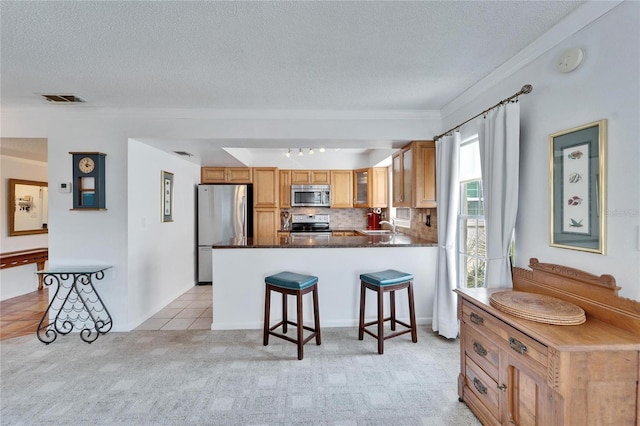 kitchen featuring backsplash, stainless steel appliances, a textured ceiling, light carpet, and kitchen peninsula