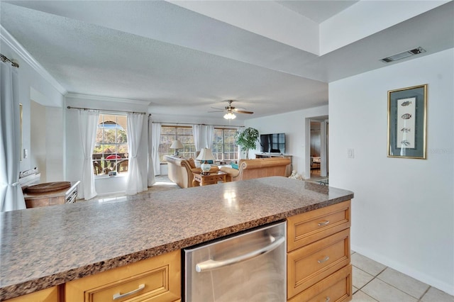 kitchen with a textured ceiling, light tile patterned floors, light brown cabinets, stainless steel dishwasher, and ornamental molding