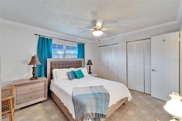 carpeted bedroom featuring crown molding, a textured ceiling, and two closets