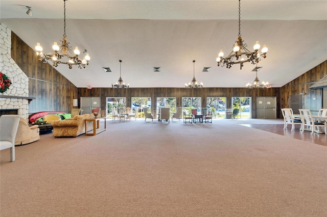 living room with a stone fireplace, high vaulted ceiling, carpet, and wooden walls