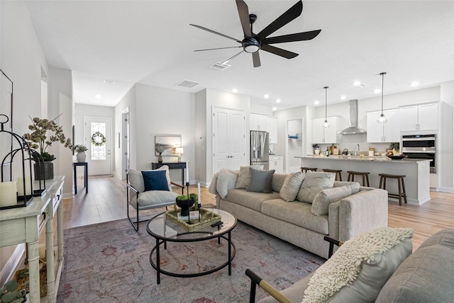 living room with hardwood / wood-style flooring, ceiling fan, and sink