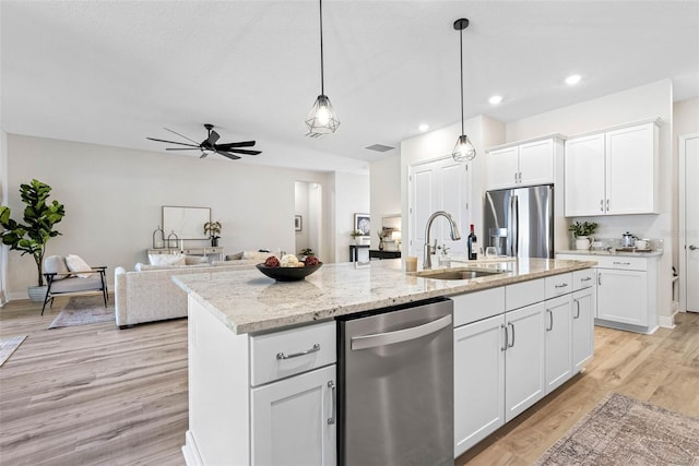 kitchen featuring sink, stainless steel appliances, an island with sink, and white cabinets