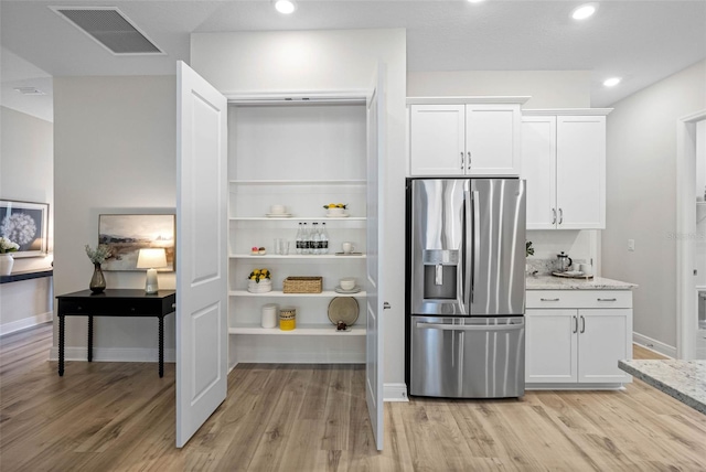 kitchen featuring white cabinetry, stainless steel fridge with ice dispenser, light stone countertops, and light hardwood / wood-style floors