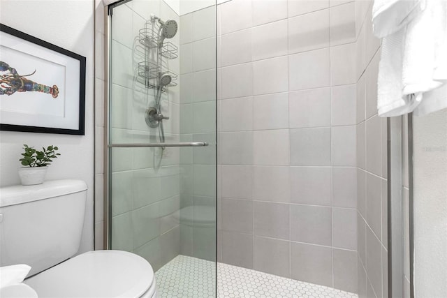 bathroom featuring a shower with shower door and toilet