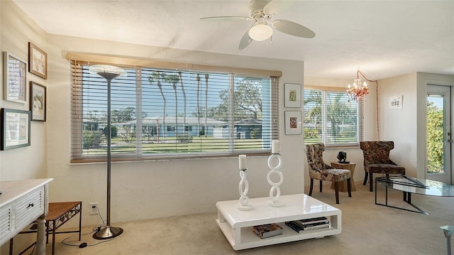 living area with ceiling fan with notable chandelier and light carpet