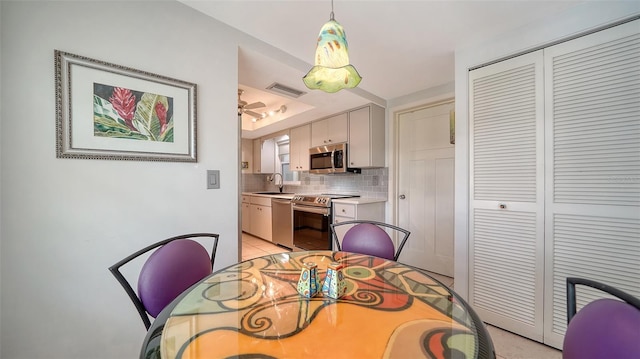 dining area with sink, a tray ceiling, and ceiling fan