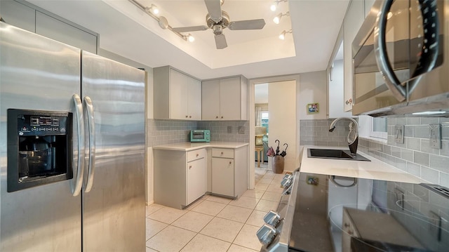 kitchen featuring light tile patterned flooring, sink, tasteful backsplash, a raised ceiling, and stainless steel appliances