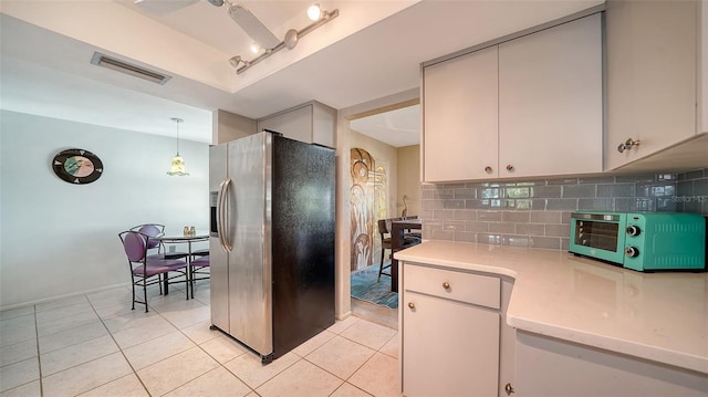 kitchen featuring decorative light fixtures, white cabinets, stainless steel fridge, decorative backsplash, and light tile patterned floors