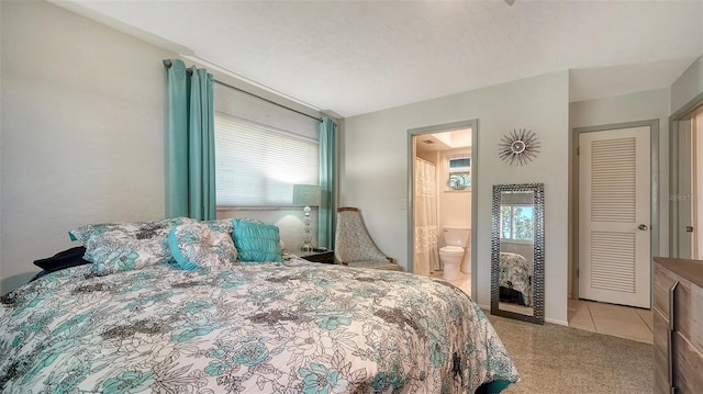 carpeted bedroom featuring a textured ceiling and ensuite bathroom