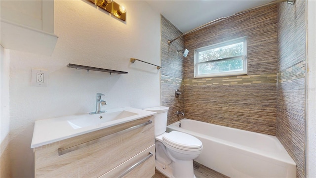 full bathroom featuring vanity, tiled shower / bath, and toilet