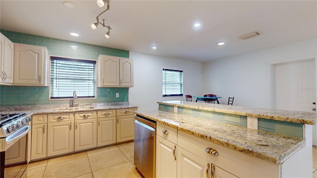 kitchen with tasteful backsplash, light stone countertops, appliances with stainless steel finishes, and sink