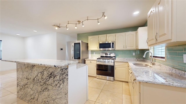 kitchen featuring sink, light stone counters, light tile patterned floors, appliances with stainless steel finishes, and backsplash