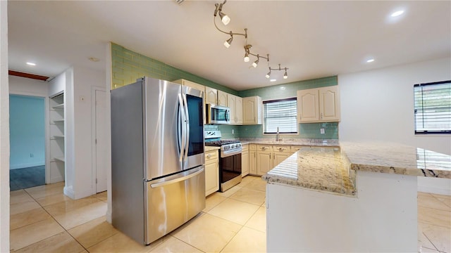 kitchen with sink, light stone counters, light tile patterned floors, appliances with stainless steel finishes, and decorative backsplash