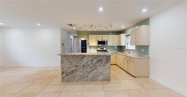 kitchen featuring sink, a center island, stainless steel appliances, light stone countertops, and decorative backsplash