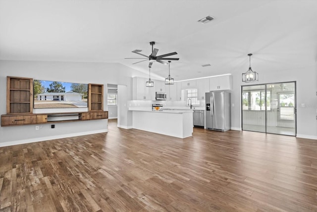 unfurnished living room featuring ceiling fan with notable chandelier, sink, vaulted ceiling, and hardwood / wood-style floors