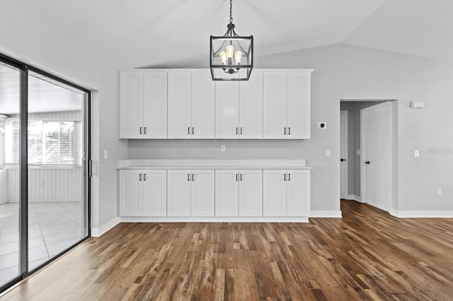 kitchen with vaulted ceiling, pendant lighting, white cabinetry, hardwood / wood-style flooring, and a notable chandelier