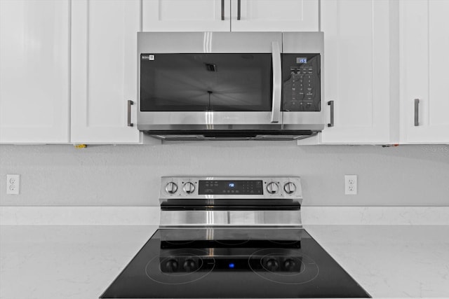 kitchen featuring white cabinetry, light stone counters, and appliances with stainless steel finishes