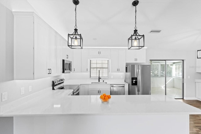 kitchen with hanging light fixtures, appliances with stainless steel finishes, sink, and kitchen peninsula