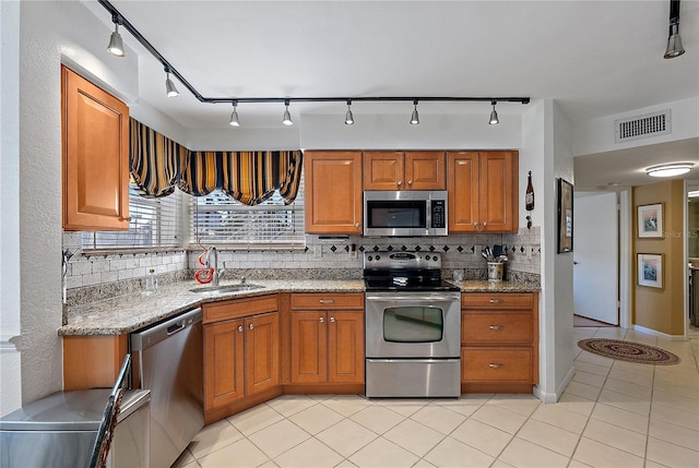 kitchen with sink, appliances with stainless steel finishes, tasteful backsplash, light stone countertops, and light tile patterned flooring