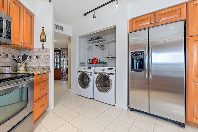 kitchen featuring stainless steel appliances, tasteful backsplash, light tile patterned floors, and independent washer and dryer