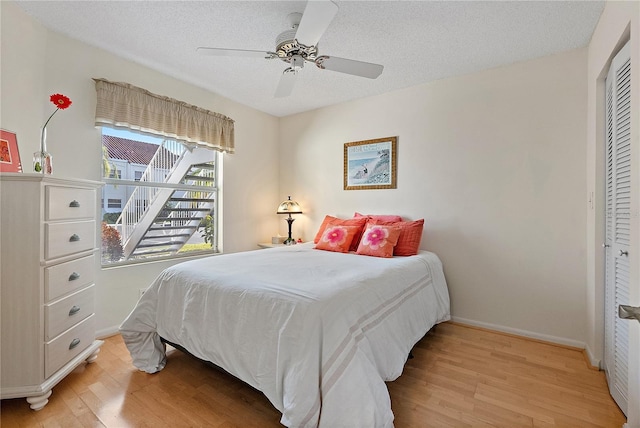 bedroom featuring ceiling fan, a closet, a textured ceiling, and light wood-type flooring