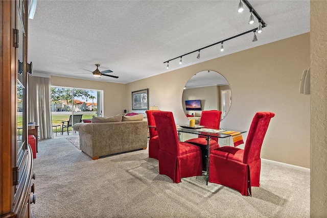 carpeted dining space featuring ceiling fan, rail lighting, and a textured ceiling