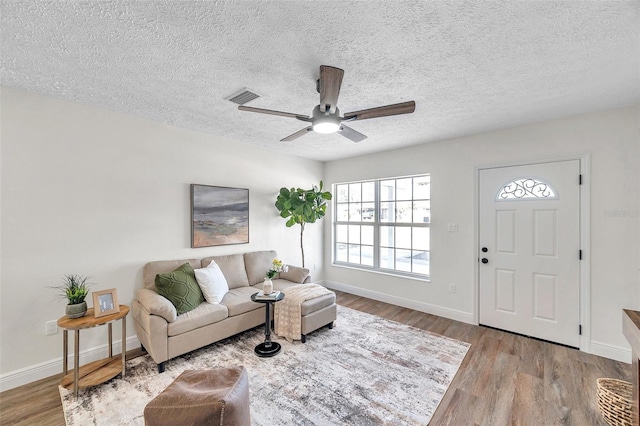 living room with a textured ceiling, light hardwood / wood-style floors, and ceiling fan