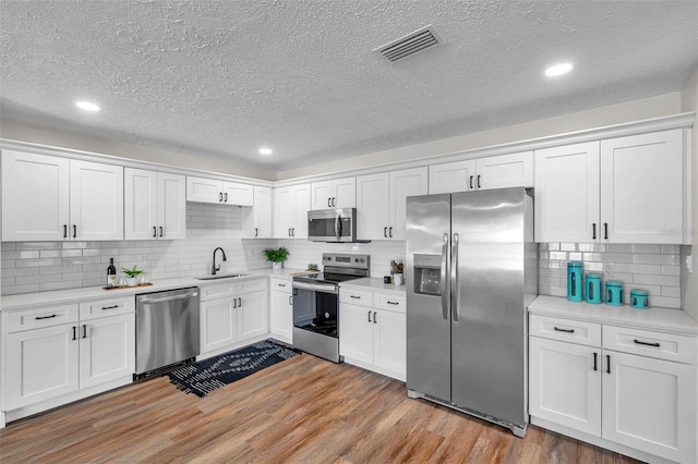 kitchen featuring white cabinetry, sink, light wood-type flooring, and appliances with stainless steel finishes