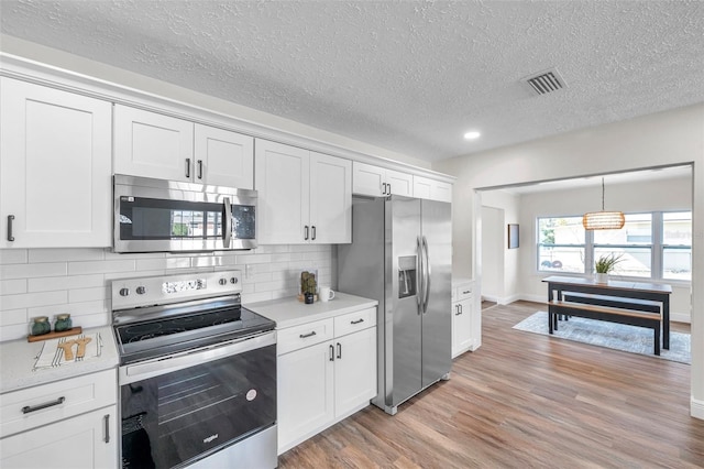 kitchen featuring stainless steel appliances, white cabinetry, and light hardwood / wood-style flooring