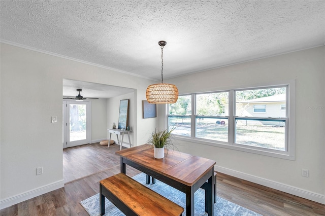 dining room with crown molding, wood-type flooring, and a textured ceiling