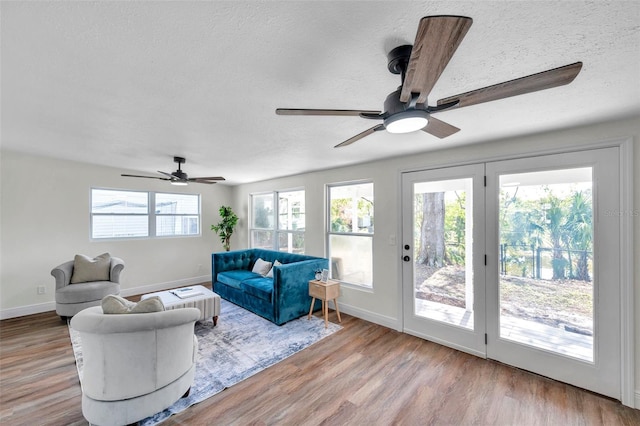 living room with ceiling fan, a textured ceiling, and light wood-type flooring