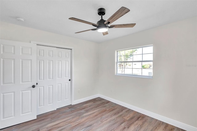 unfurnished bedroom with hardwood / wood-style floors, ceiling fan, and a closet