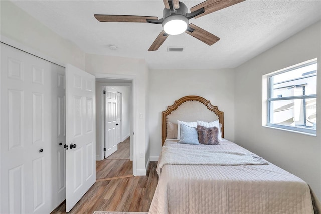 bedroom with dark wood-type flooring, a closet, ceiling fan, and a textured ceiling