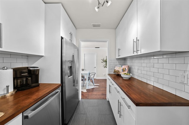 kitchen featuring white cabinetry, backsplash, wooden counters, and appliances with stainless steel finishes