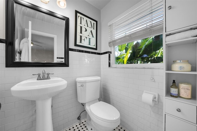 bathroom with toilet and tile walls