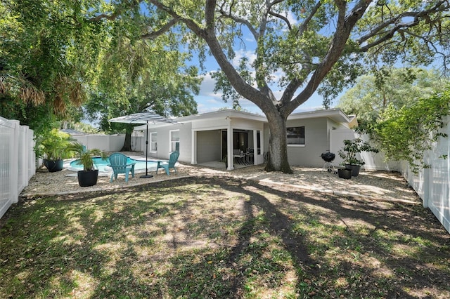 back of property with a fenced in pool and a patio