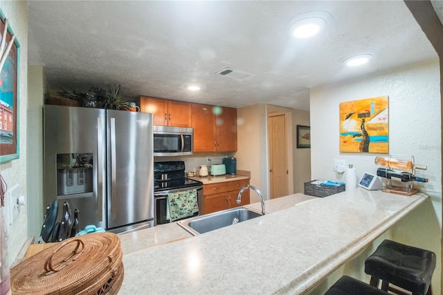 kitchen with appliances with stainless steel finishes, sink, a breakfast bar, and kitchen peninsula