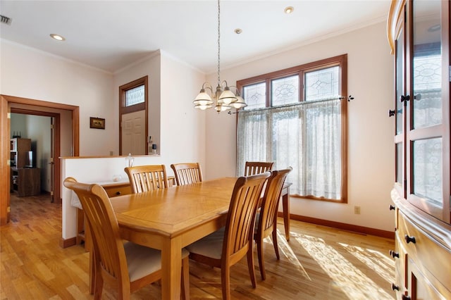 dining space with a notable chandelier, ornamental molding, and light wood-type flooring