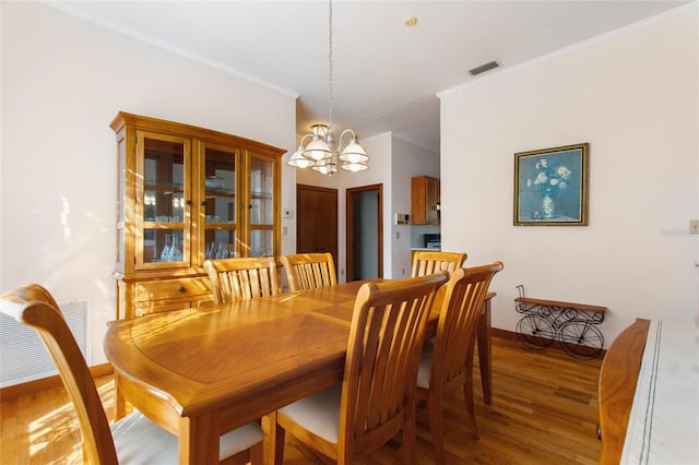 dining area featuring an inviting chandelier, hardwood / wood-style floors, and ornamental molding