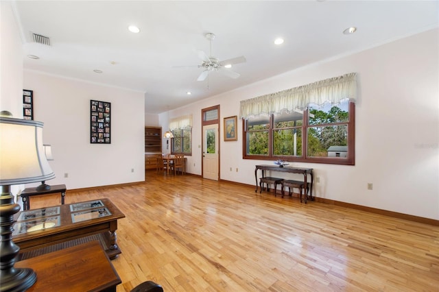 living room with light hardwood / wood-style flooring, ornamental molding, and ceiling fan