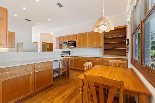 kitchen with hanging light fixtures, stove, stainless steel fridge, and light hardwood / wood-style flooring