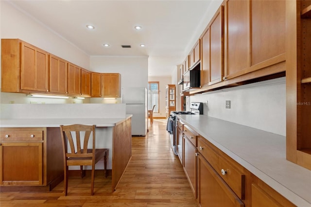 kitchen featuring white fridge, a breakfast bar, stainless steel stove, and light wood-type flooring